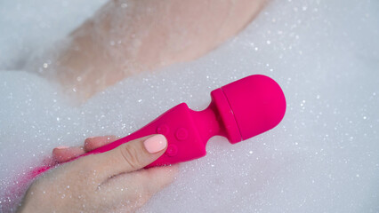Woman lies in a bubble bath and uses a vibrator. 