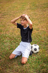 Young soccer player on his knees stunned after losing the game