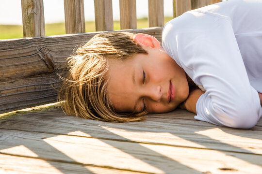 Cute little boy peacefully asleep outside on a beach house patio