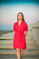 Portrait of a young beautiful girl in a red dress outdoors in summer.