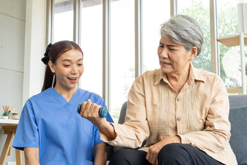 Young physical therapist female help aged female patient workout with dumbbell