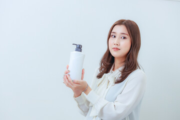 シャンプーボトルを持った若い女性