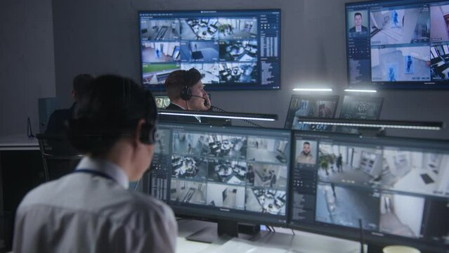 Female security officer watches security cameras with AI facial recognition with male colleagues. Monitoring center workers. Computer monitors and big digital screens with CCTV cameras video footage.
