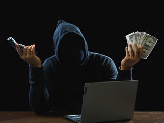 Fototapeta Hacker spy man wearing a black shirt, sitting on a chair and a table, is a thief, hands holding money, counting the amount obtained from hijacking or robbing, in pitch-black room. obraz