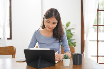 Work from home concept, Business women taking notes while reads data on tablet in living room