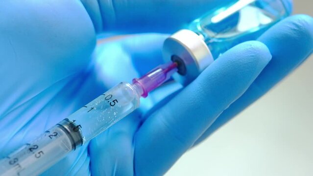doctor's hand holds a syringe and a blue vaccine bottle at the hospital. Health and medical concepts.