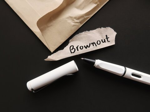Torn office envelope and pen writing word BROWNOUT, Employees feel overworked, demotivated and disengaged &ndash; which is essentially the stage before burnout