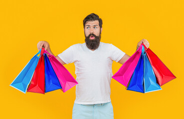 photo of shocked shopaholic man at shopping hold bags isolated on yellow