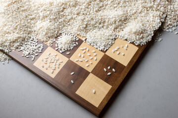 A wooden chessboard with one grain of rice on the first square, doubling at each square. The tale...
