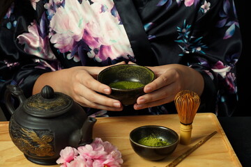 Woman tea master in kimono performs tea ceremony. Matcha green tea powder with a bamboo whisk and...