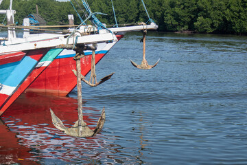 the anchor of the fishing boat is being lifted because the ship is anchored at the wharf