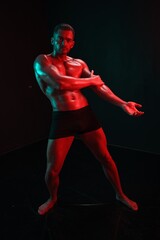 Fototapeta na wymiar Man bodybuilder posing muscles with nude fitness torso, isolated on black background in neon light. Advertising, sports, active lifestyle, colored light, competition, challenge concept. 