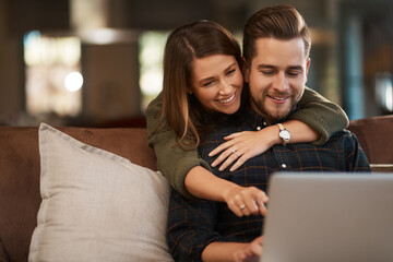 Relax, laptop and social media with a couple on a sofa in the living room of their home together. Computer, web or internet with a man and woman hugging while bonding in their house on the weekend