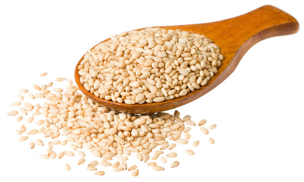 Roast white sesame seeds in the wooden spoon, isolated on white background.
