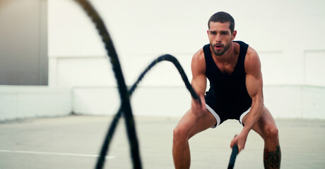 Man, fitness and battle ropes in training, exercise or workout for physical wellness outdoors. Fit,...