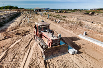 Bulldozer during the construction of a new road. Top view of a powerful working bulldozer. Earthmoving equipment for road works, land clearing, leveling, trenching.