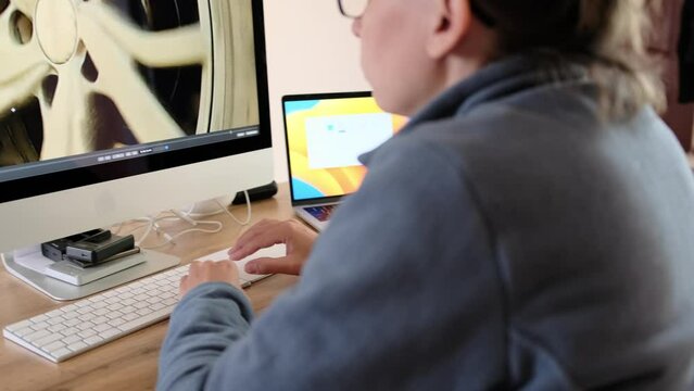 Girl in a cozy home environment works at a personal computer edits video. Young woman freelancer using keyboard computer at home.