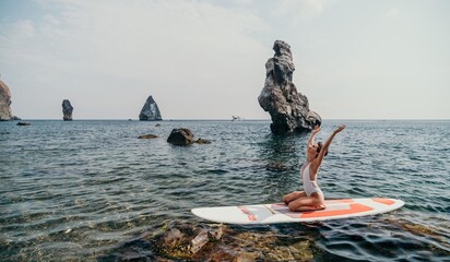 Woman sup yoga. Happy sporty woman practising yoga pilates on paddle sup surfboard. Female...