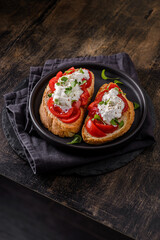 two bruschetta with tomatoes on a wooden background