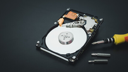 Memory repair concept. Repair of storage systems. Hard disk repair. Hard disk with screwdriver on dark background