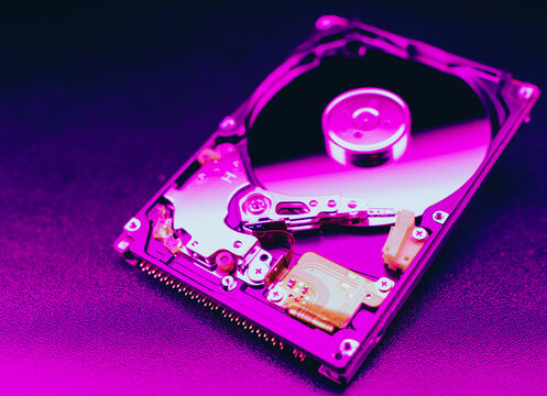 An open hard disk disassembled HDD of a computer or laptop lies on a purple surface. Computer hardware and accessories. Hard disk storage.