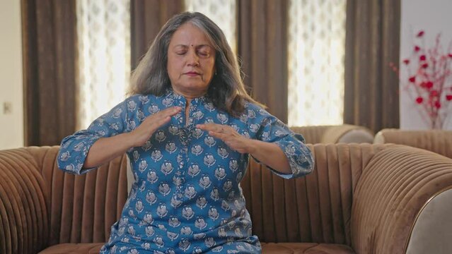 Old Indian woman doing breathe in breathe out exercise