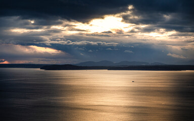 Dramatic sunlight through cloudy sky over sea surface, Seattle, USA.