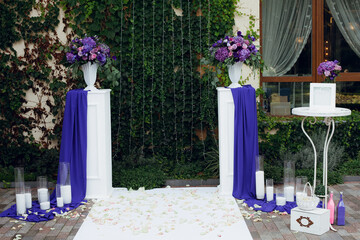 Wedding arch in white and blue colors with fresh flowers and candles. Creative image for your design or illustrations.