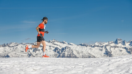 A male mountain runner trains in the snow