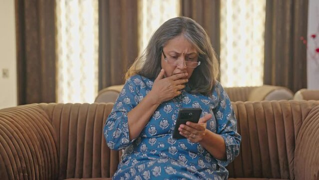 Upset Indian old woman sees a shocking news on mobile phone