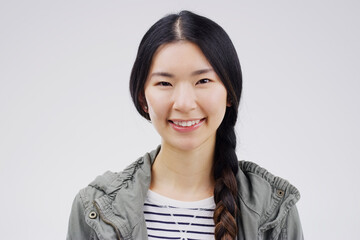 Portrait, happy or smile with an asian woman in studio on white background for japanese fashion. Face, contemporary or style with an attractive young female person looking confident in trendy clothes