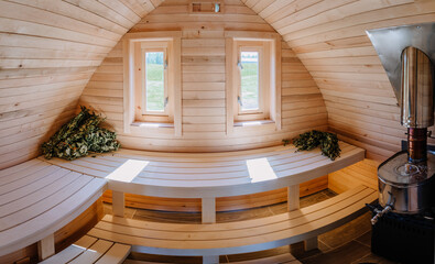 Wooden Igloo sauna from the inside, oven and sauna broom, panorama view