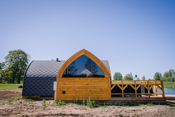 Igloo sauna made of wood with a boardwalk by the lake