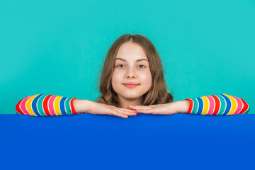 child smile behind blank blue paper with copy space for advertisement