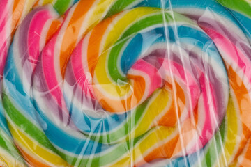extreme closeup of colorful lollipop candy in transparent plastic packaging on white background
