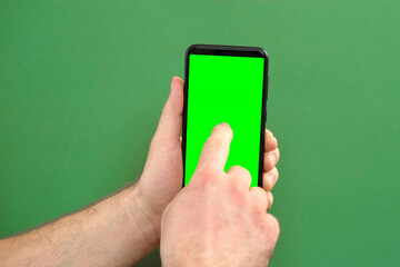 Young man hand use smartphone with green screen on green background. Gestures pack. Male hand touching, clicking, tapping swiping on black phone chroma key display. Close up Device. Modern Technology