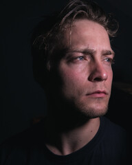 A mysterious man in a dark room being lost in thought