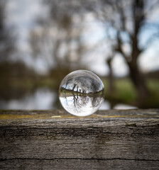 Crystal lens on wooden beam and landscape
