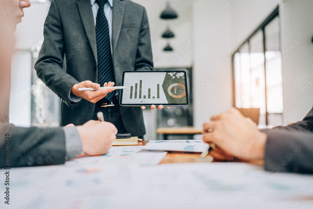 Wall mural portrait of young asian business team presents business profits to colleagues at meeting, explaining business turn over on flipchart to coworkers in office with using tablet.