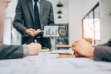portrait of young asian business team presents business profits to colleagues at meeting, explaining business turn over on flipchart to coworkers in office with using tablet.