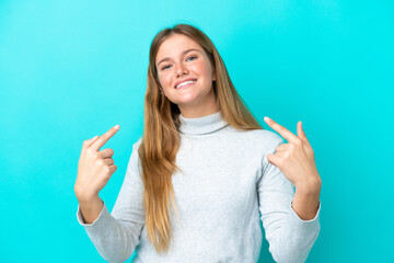 Young blonde woman isolated on blue background giving a thumbs up gesture