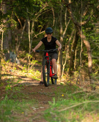 Fototapeta premium Female cyclist on her mountain bike riding through the hills on a sunny day.