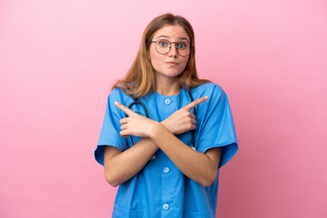 Young surgeon doctor woman isolated on pink background pointing to the laterals having doubts