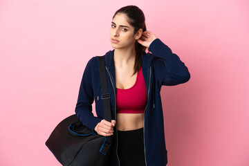 Young sport caucasian woman with sport bag isolated on pink background having doubts