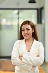 Portrait of female executive wearing formal stylish clothes standing with crossed arms and smiling to camera