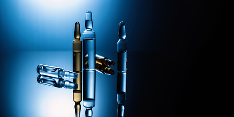 Medical drugs, ampoules with injections, vaccination, health care, close-up, dark background with blue backlight, place for text