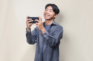 Fototapeta premium Young Asian man showing surprised facial expression while reading message on his mobile phone