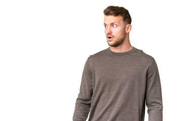 Obraz premium Young handsome caucasian man over isolated chroma key background doing surprise gesture while looking to the side