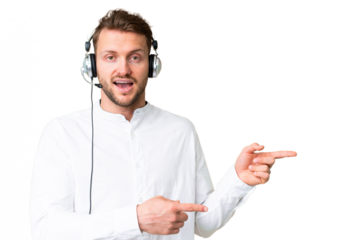 Telemarketer caucasian man working with a headset over isolated chroma key background surprised and pointing side