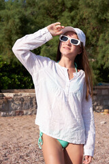 Stylish teenager girl with freckles is resting on the beach in summer sunny day.